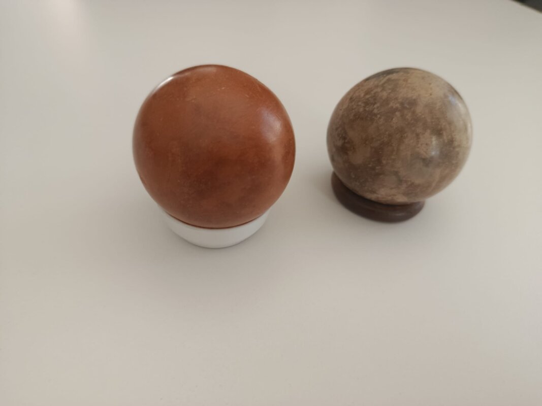 Deux dorodangos côte à côte : à gauche une sphère brun-rouge polie, brillante, qui reflète la lumière ; à droite une sphère grise mate non polie — métaphore visuelle des deux stades du travail GEO